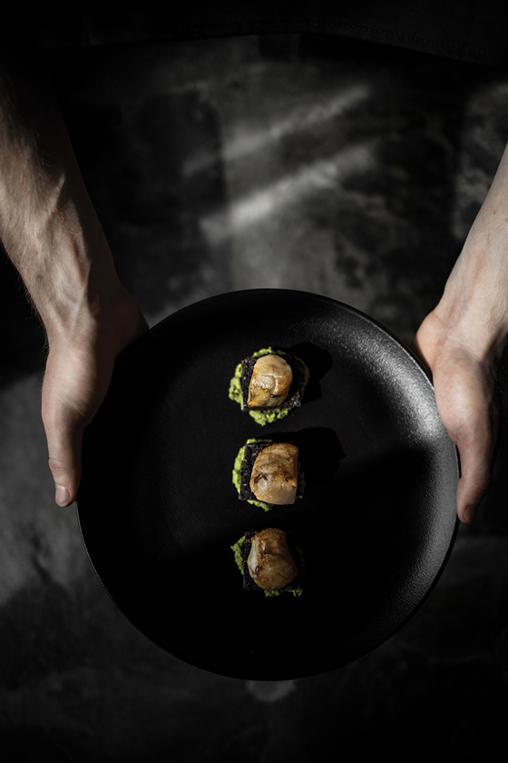 Canapés on a black plate by The Lunchbox Boys.