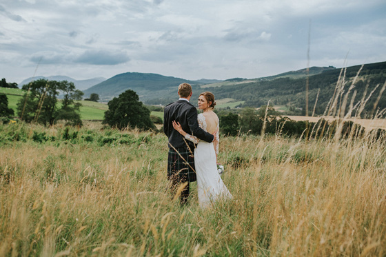 Bride and groom looking at the hills together whilst bride looks back