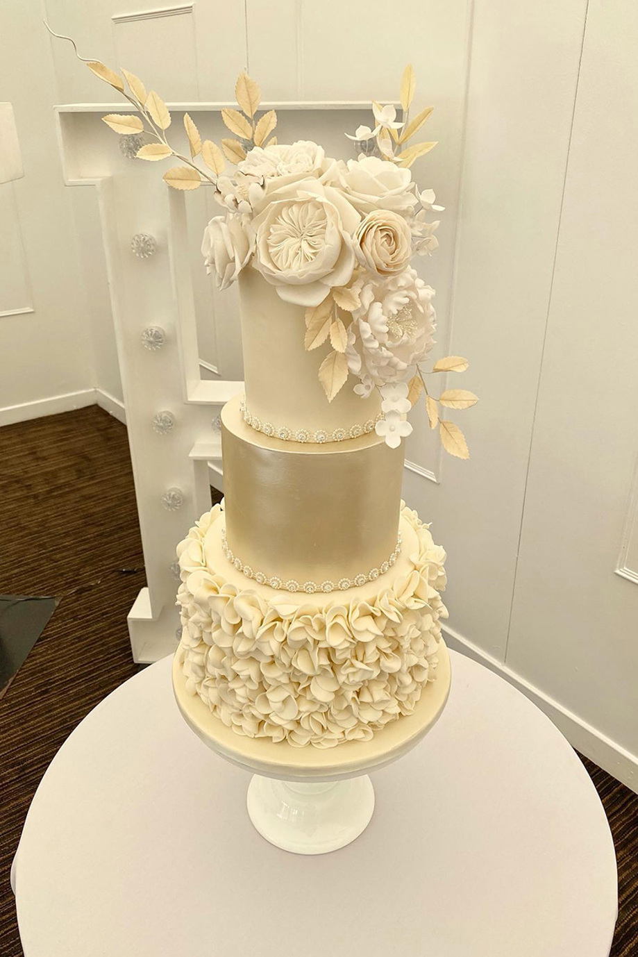 Cream three-tier cake with cream flowers and decorative branches