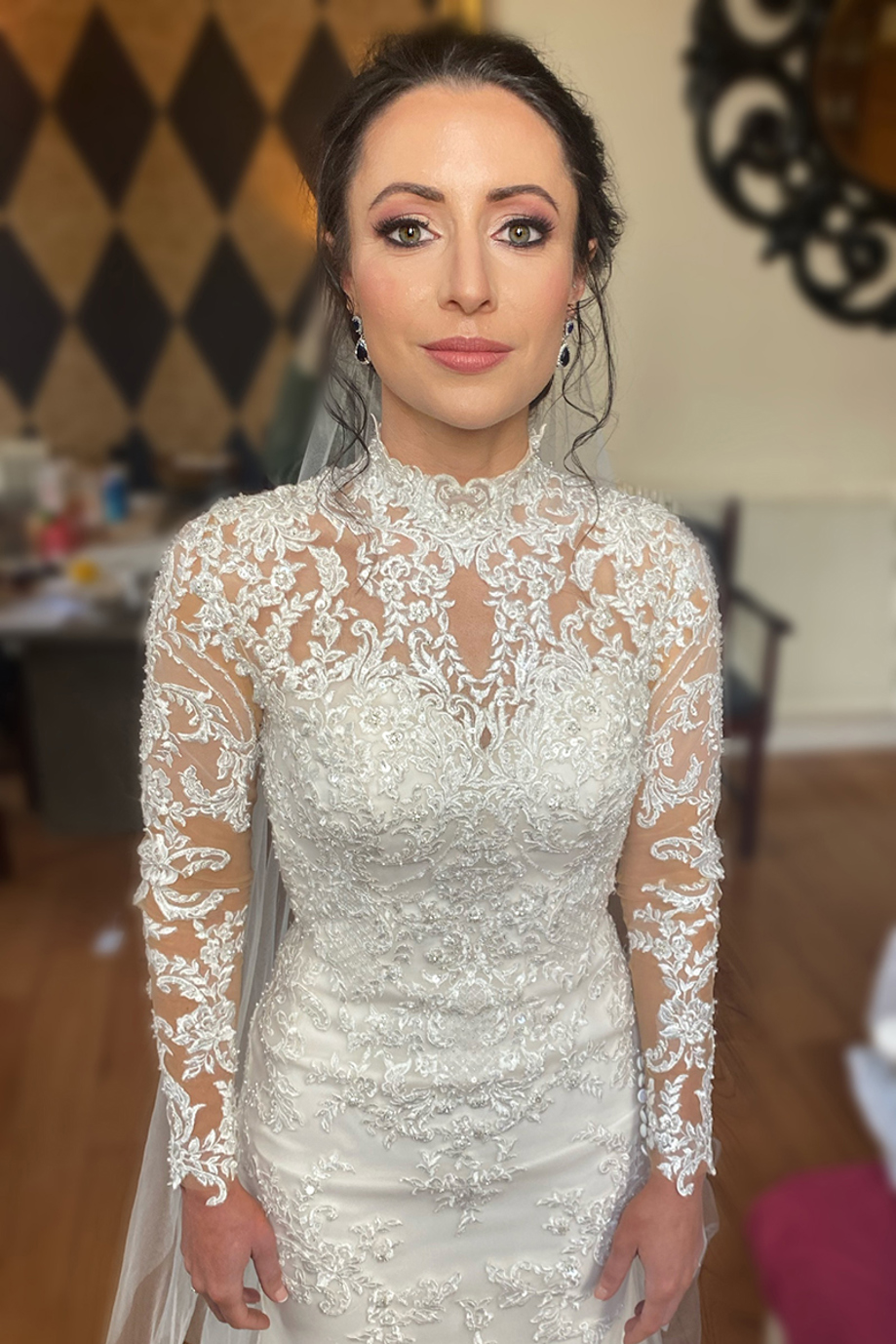 Bride in long-sleeved lace dress and veil with a wash of pink on her eyelids