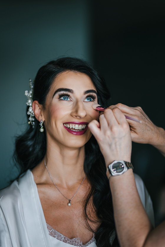 Final touches are added to brides makeup with dark pink lipstick