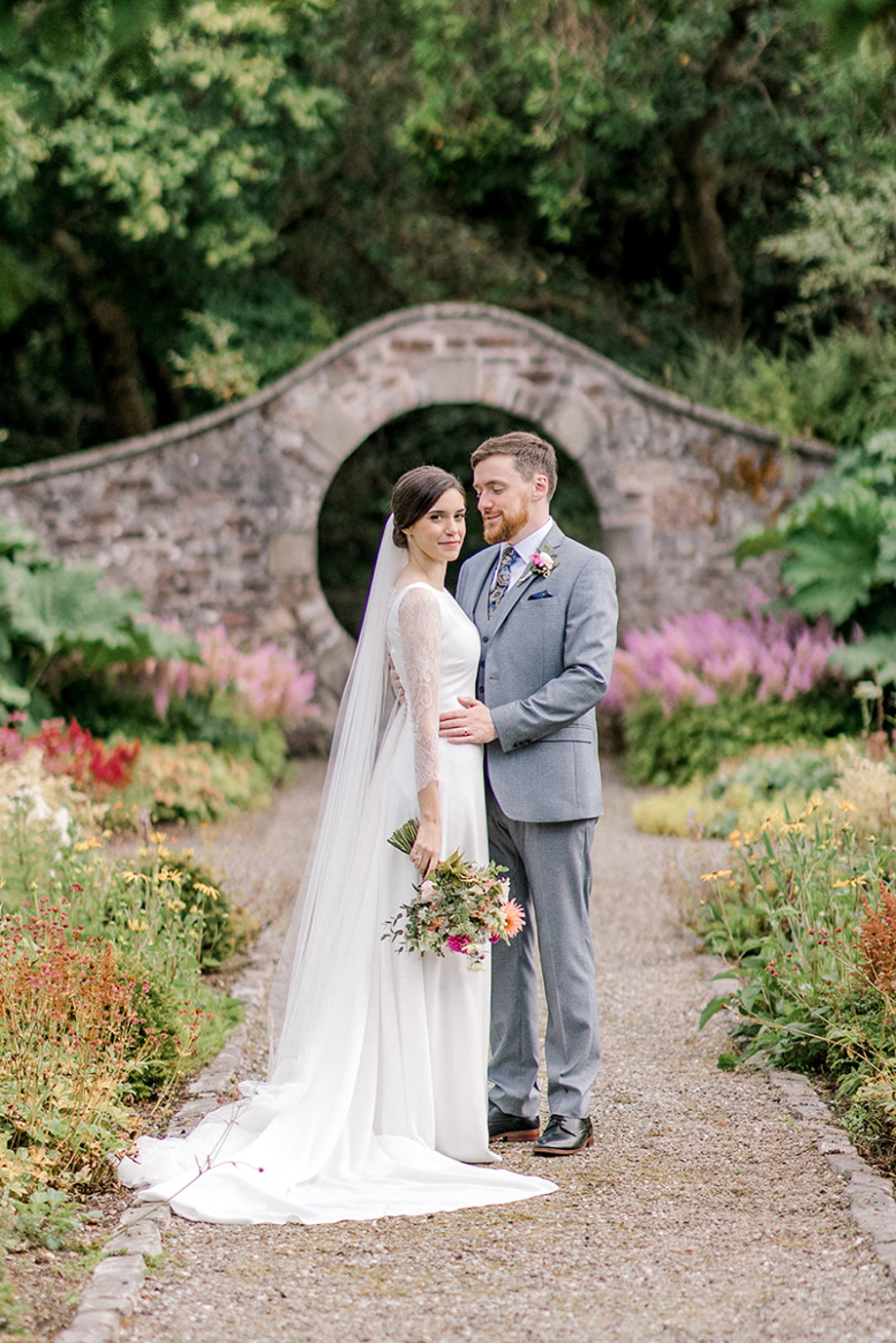 Bride and groom portrait in a Scottish garden with a stone arch backdrop