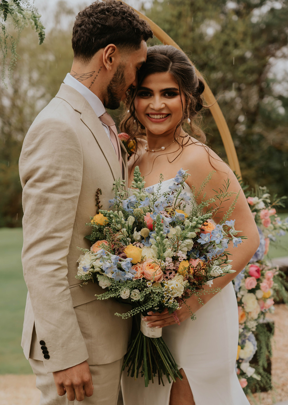 Bride holding spring pastel bouquet and standing with groom