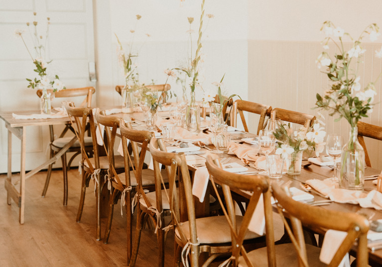 Rustic wedding meal set up with long tables decorated with white flowers in vases