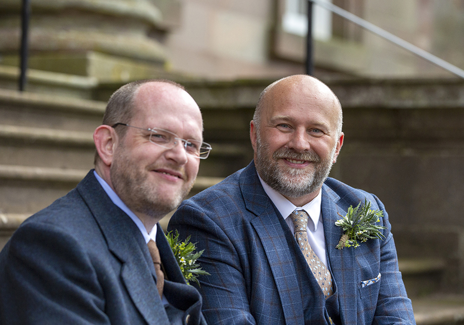 Two groomsmen sitting on stairs smiling