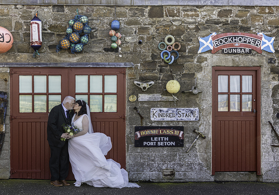 Bride and groom stand outside red door