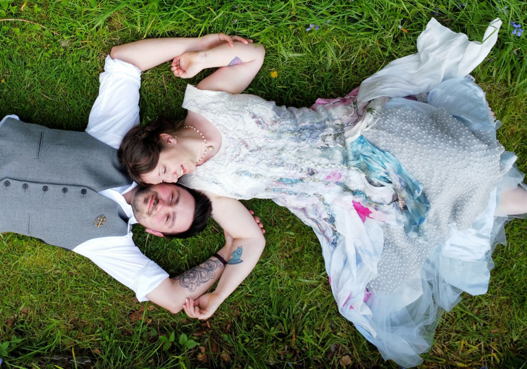 Bride adn groom laying on grass together. Drone wedding photograahy 