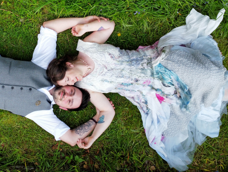 Bride adn groom laying on grass together. Drone wedding photograahy 