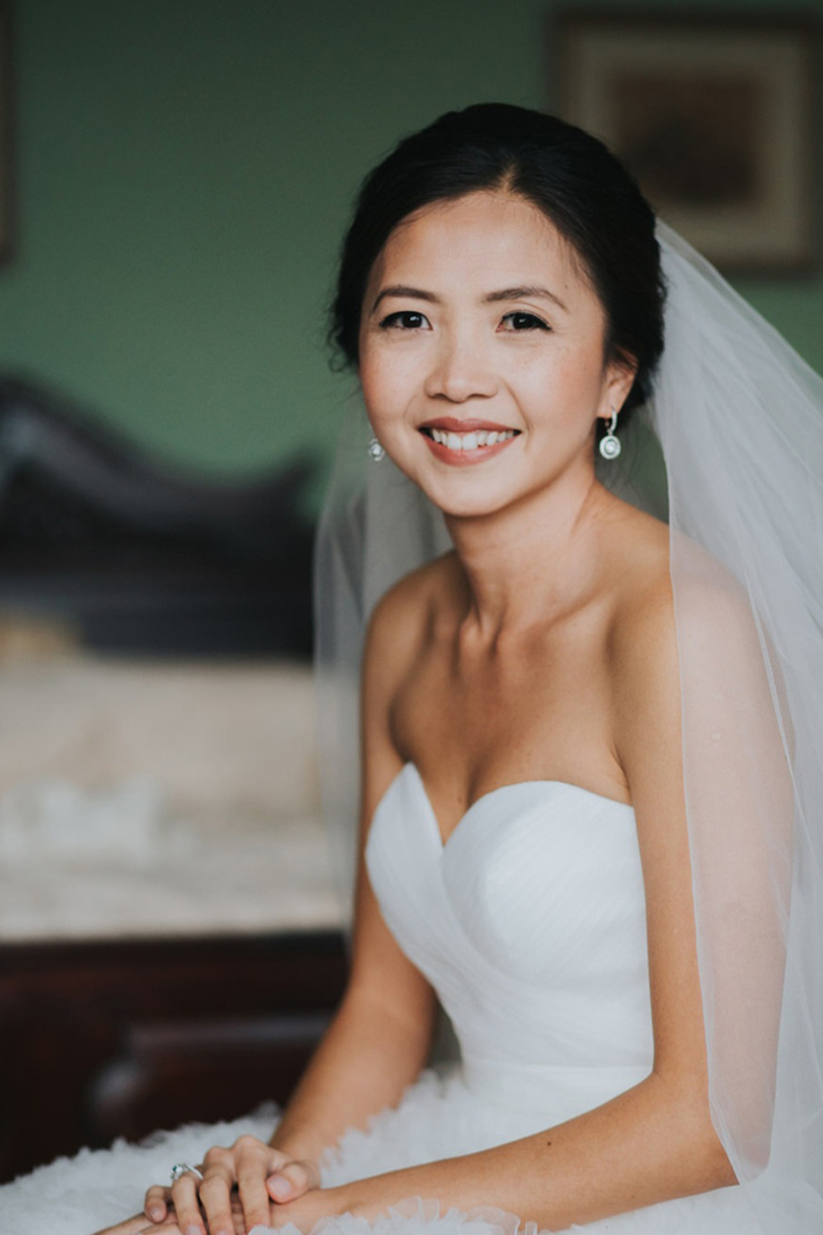 Bride smiles in hotel room before her wedding, makeup is by Jennifer Louise Studio.
