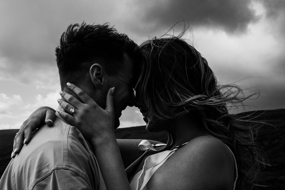 Bride embraces grooms face in black and white.