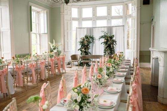 Image of wedding meal set up with pink chair ribbons and floral centrepieces