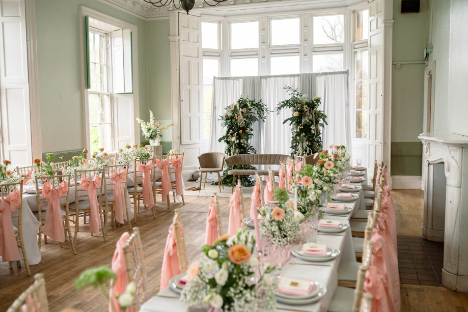 Image of wedding meal set up with pink chair ribbons and floral centrepieces