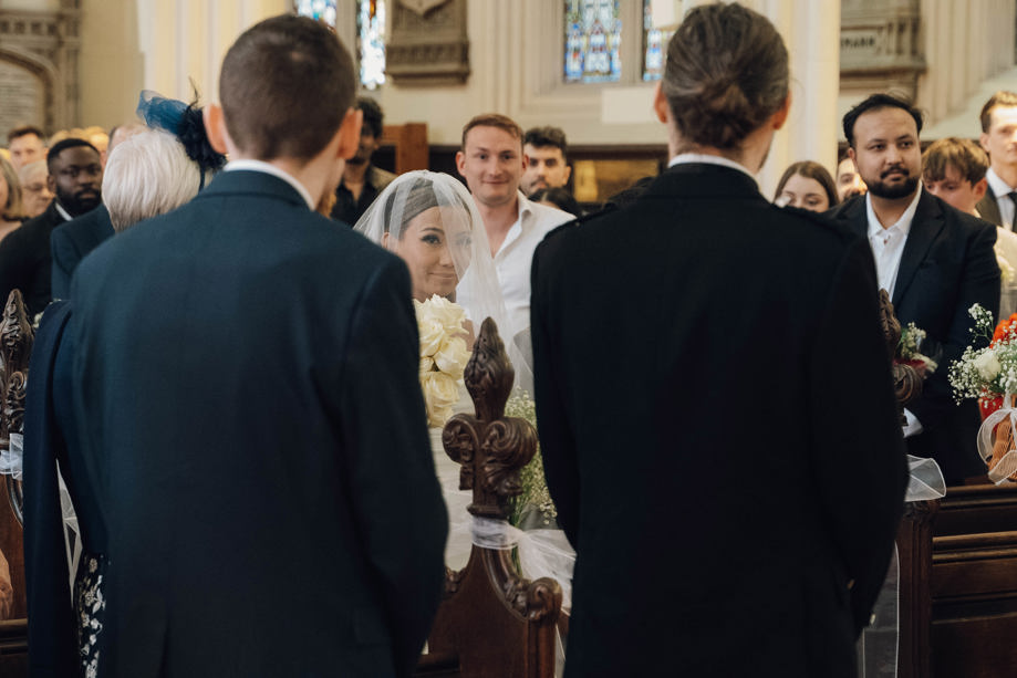 Bride smiles as she walks down the aisle by Aela Photography
