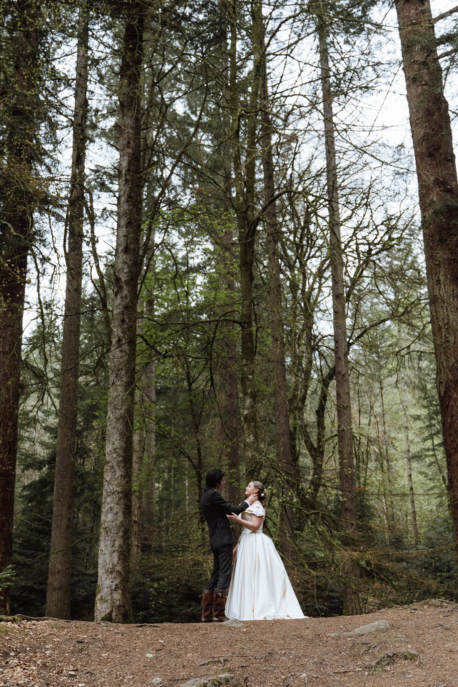 Bride and groom embrace amongst trees by Aela Photography