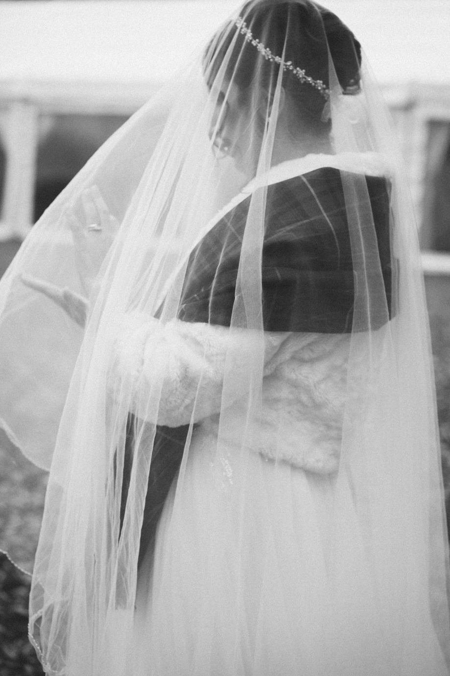 Black and white image of side view of a bride with veil over her face