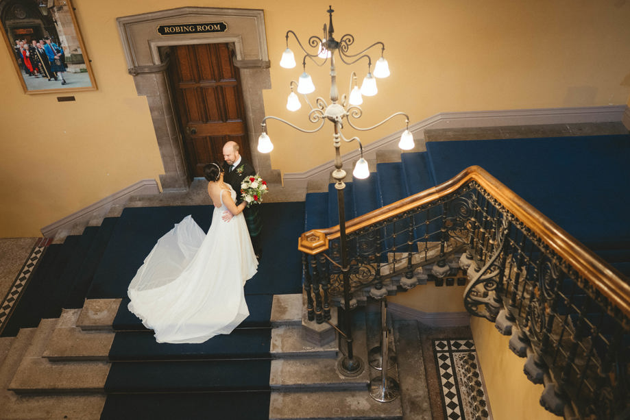 Bride and groom embrace on stairs landing