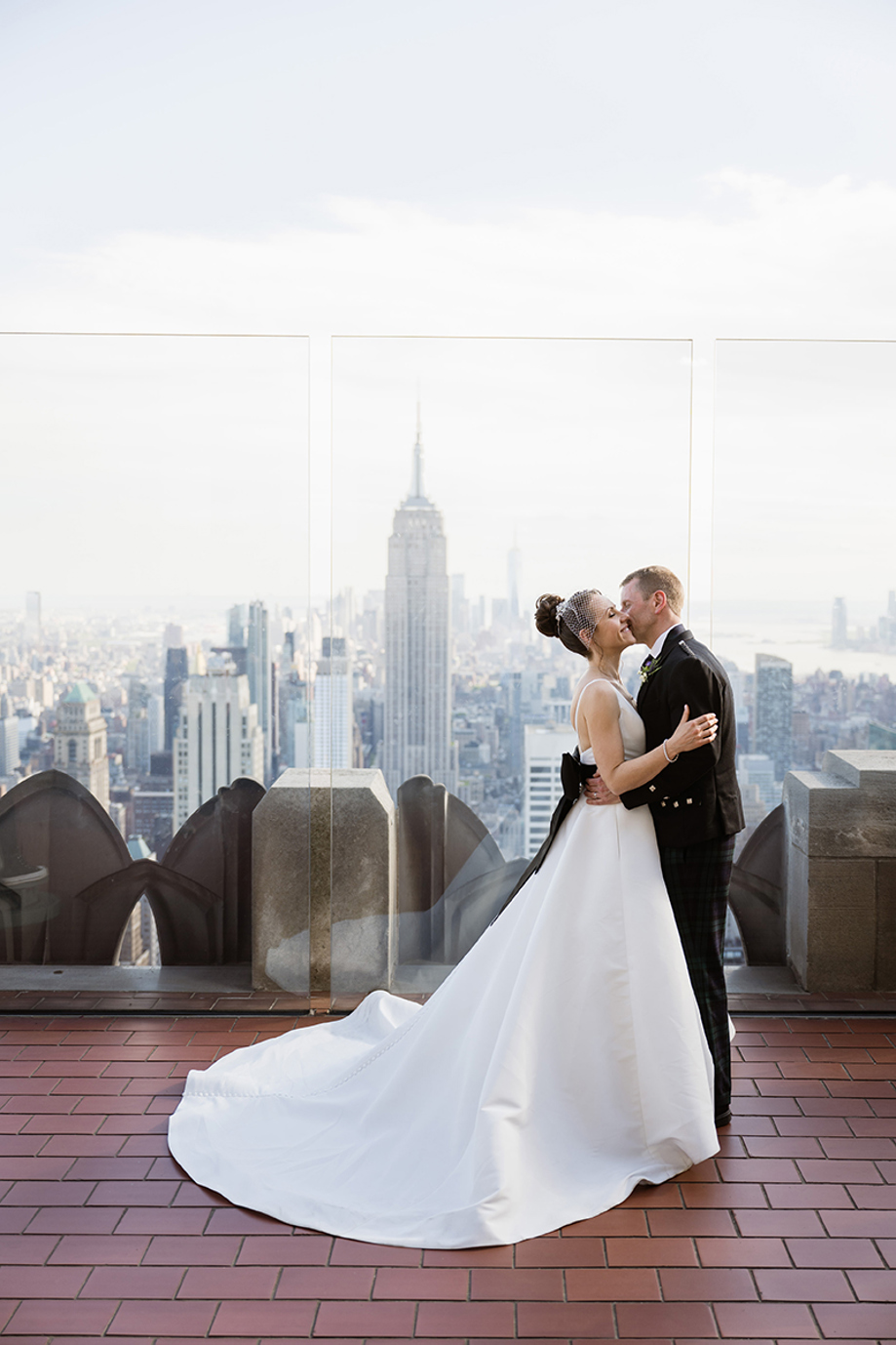 Bride and groom embracing at the top of the Empire State Building with New York skyline views