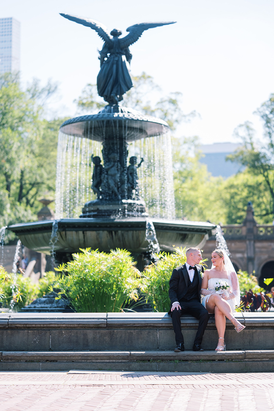 Bride and groom sitting beside Bethesda Fountain in Central Park on their wedding day