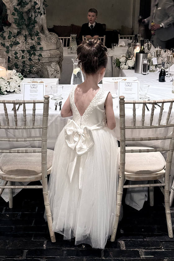 Flower girl stands between two chiavari chairs