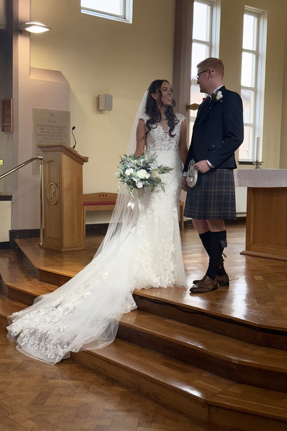 Bride and groom stand on church altar by Unveiled Moments