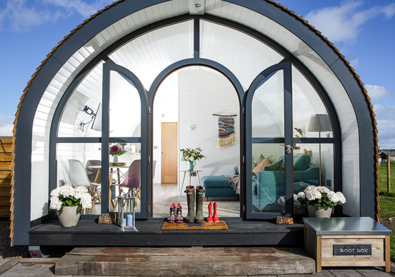 Glamping pod at Maycroft Retreat with bright, modern interiors with three pairs of welly boots outside door.