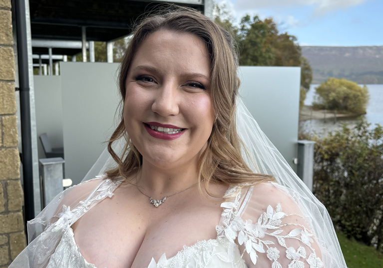 Bride smiles outside her wedding venue in her dress before the ceremony, makeup by Jill Rowan Makeup.