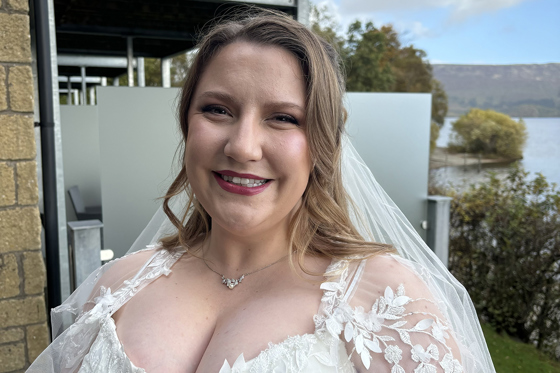 Bride smiles outside her wedding venue in her dress before the ceremony, makeup by Jill Rowan Makeup.