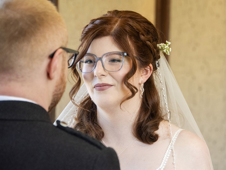 Redheaded bride and groom, both wearing glasses, at the altar. Bridal makeup by Jill Rowan Makeup in Larbert.