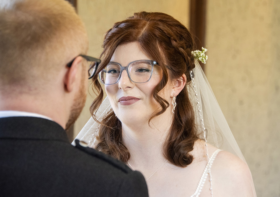 Redheaded bride and groom, both wearing glasses, at the altar. Bridal makeup by Jill Rowan Makeup in Larbert.