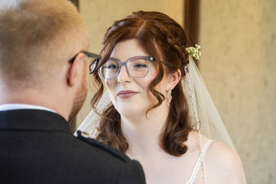 Redheaded bride and groom, both wearing glasses, at the altar. Bridal makeup by Jill Rowan Makeup in Larbert.