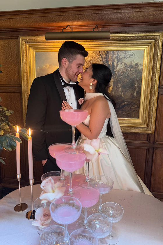 Bride and groom laugh together in front of pink cocktail tree at their Scottish wedding by wedding content creator The Perfect Day Club.
