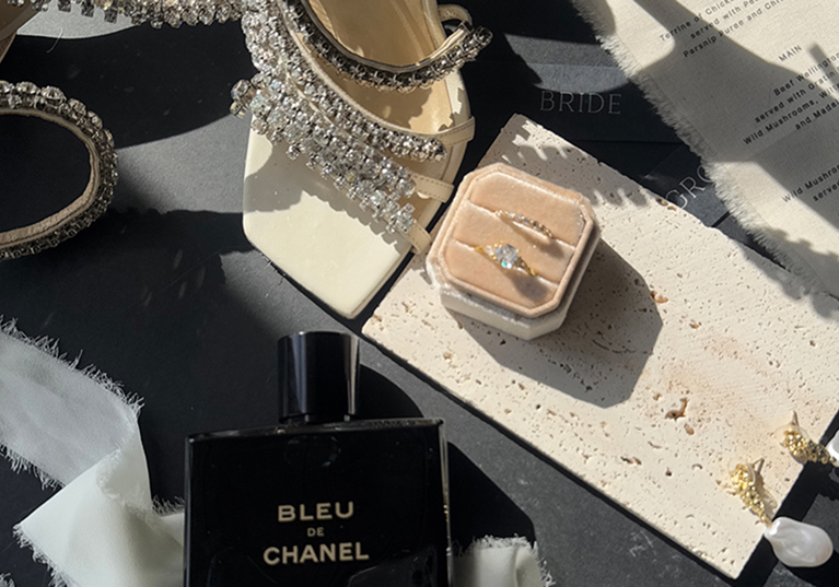 Detail shot of Jimmy Choo wedding shoes, rings, perfume and menu by The Perfect Day Club, a wedding content creator in Scotland.