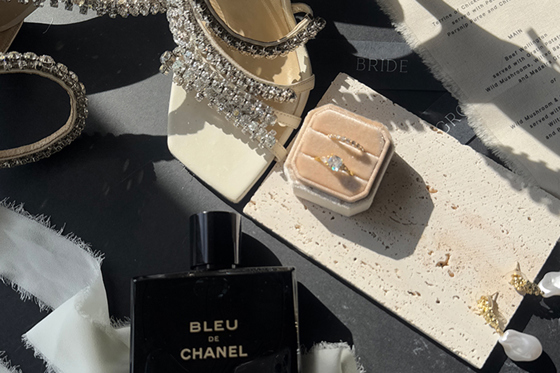 Detail shot of Jimmy Choo wedding shoes, rings, perfume and menu by The Perfect Day Club, a wedding content creator in Scotland.