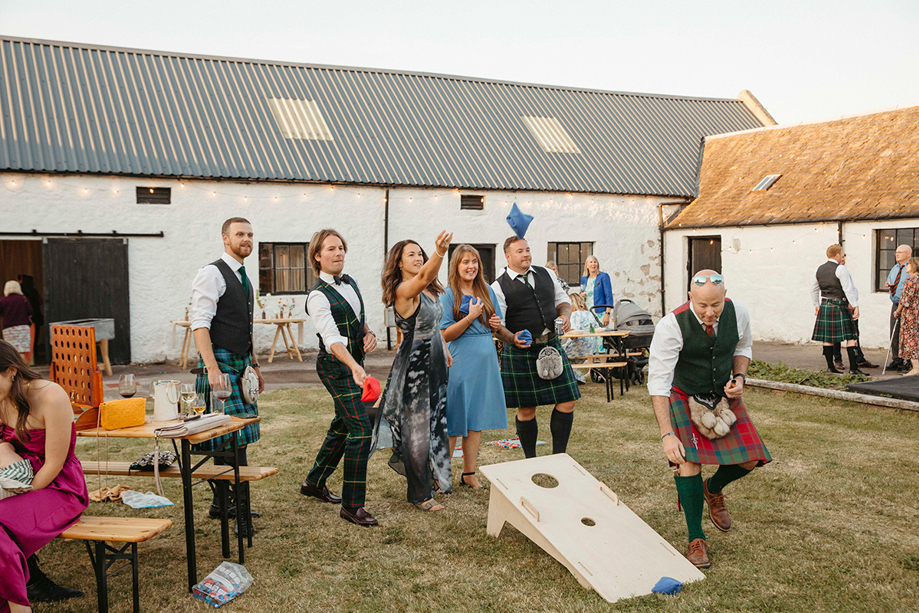 Guests play bean bag toss game outside wedding venue, organised by Scottish wedding planners Speyside Events Company.