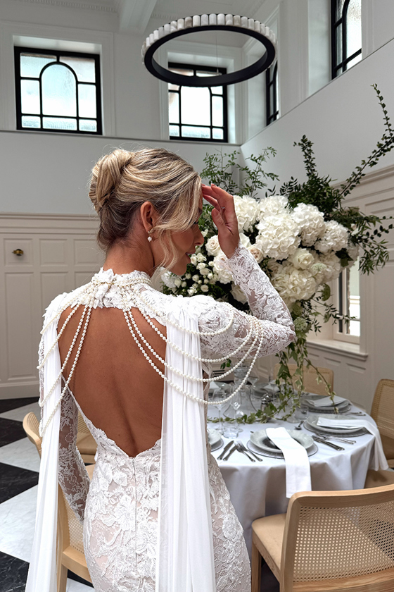 Captured by Ivoura, a wedding content creator, Emily Shak poses to show the back of her dress with draped beading.