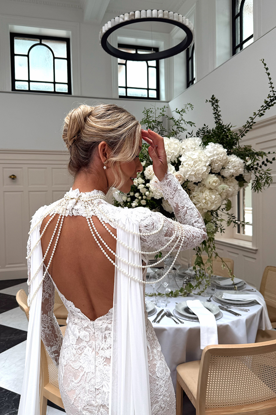 Captured by Ivoura, a wedding content creator, Emily Shak poses to show the back of her dress with draped beading.