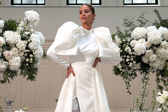 Emily Shak poses between large floral displays at The Collector's Hall in Glasgow, content captured by Elise at Ivoura.