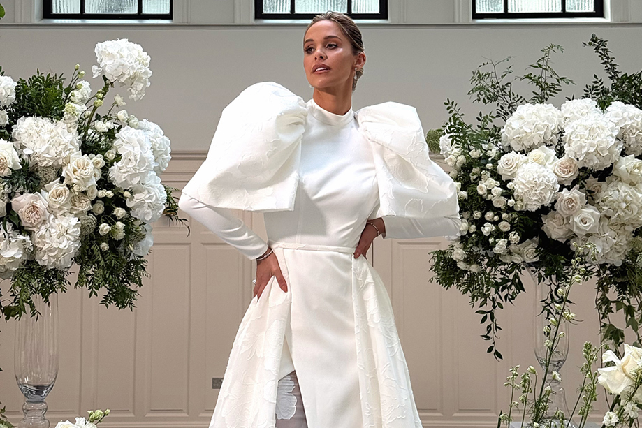 Emily Shak poses between large floral displays at The Collector's Hall in Glasgow, content captured by Elise at Ivoura.
