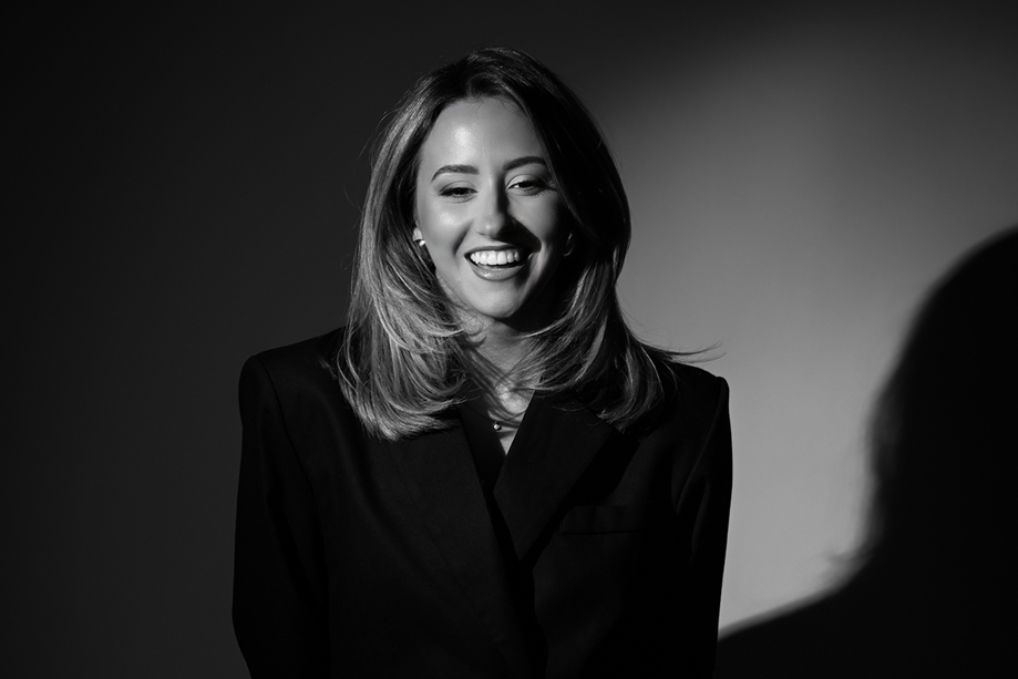 Elise, owner of Ivoura, smiles in a black and white image, wearing a black fitted suit.