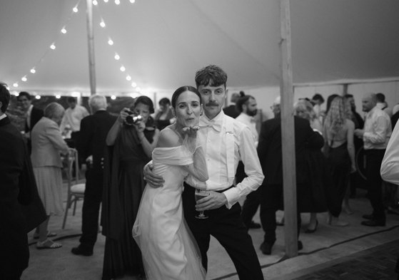 Bride and groom look to the camera and the bride blows a kiss