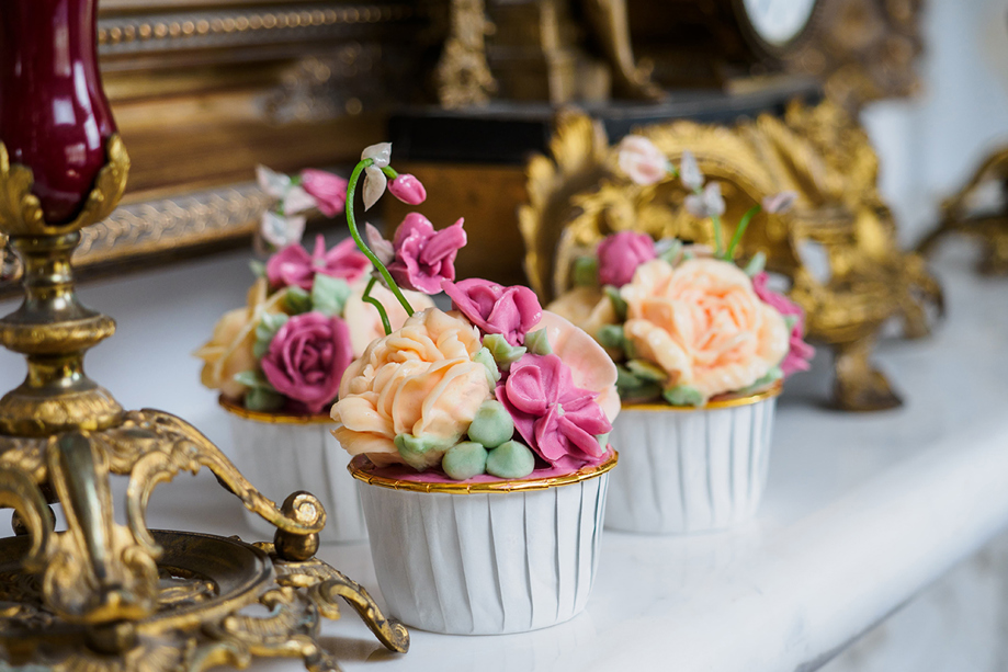 Hand-piped floral cupcakes in gold-rimmed white cupcake holders by Eclectic Luxuries