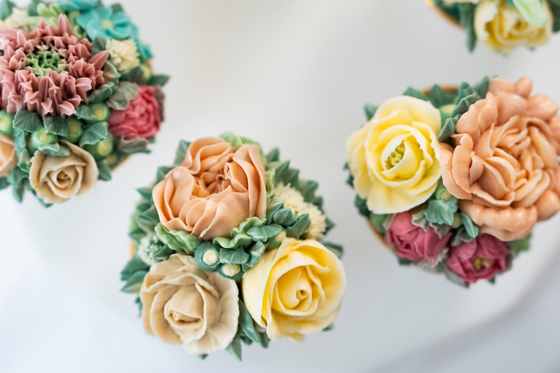 Hand-piped floral cupcakes with peach, yellow and pink flowers by Eclectic Luxuries - Artisan Couture Cakes
