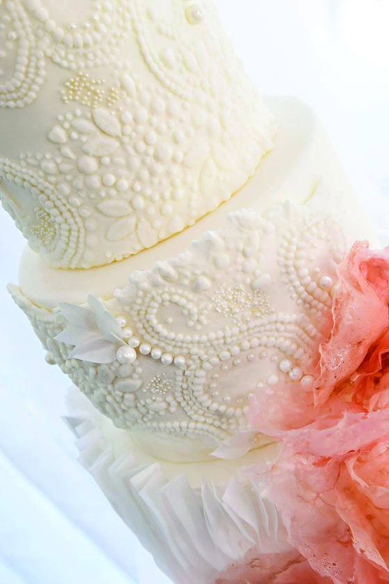 Three-tier cake inspired by the bride's wedding gown with intricate beading, ruffles and pink wafer paper by Eclectic Luxuries