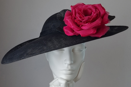 Black hat with cerise rose at Hazel Goodwin Millinery in Glasgow city centre