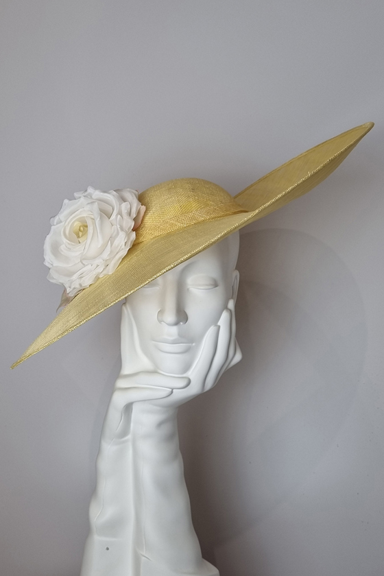 Pale yellow sidesweep hat with large cream flower at Hazel Goodwin Millinery in Glasgow city centre