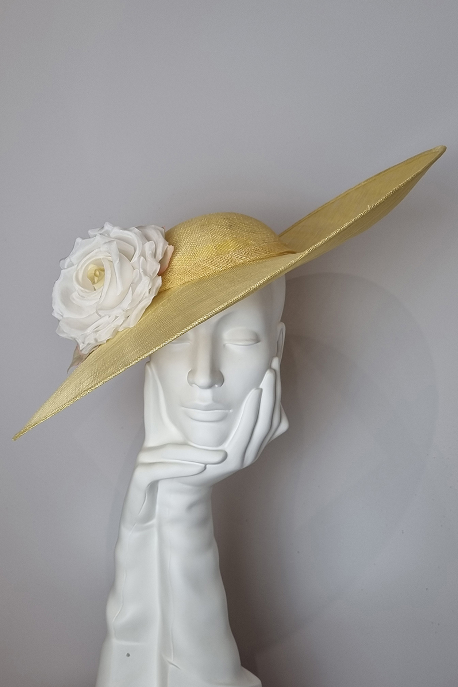 Pale yellow sidesweep hat with large cream flower at Hazel Goodwin Millinery in Glasgow city centre
