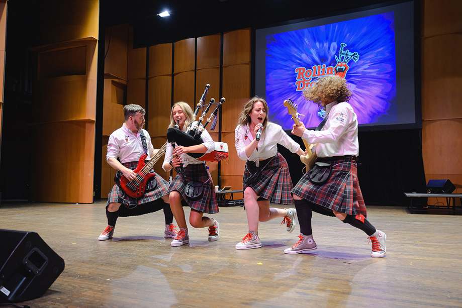 Rollin Drones on stage playing electric guitar and bagpipes while wearing kilts, booked through Hireaband