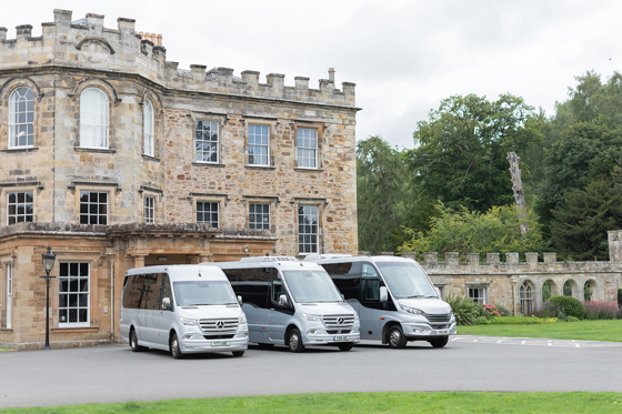 Angled view of three Anderson Black Executive Travel minibuses parked outside wedding venue