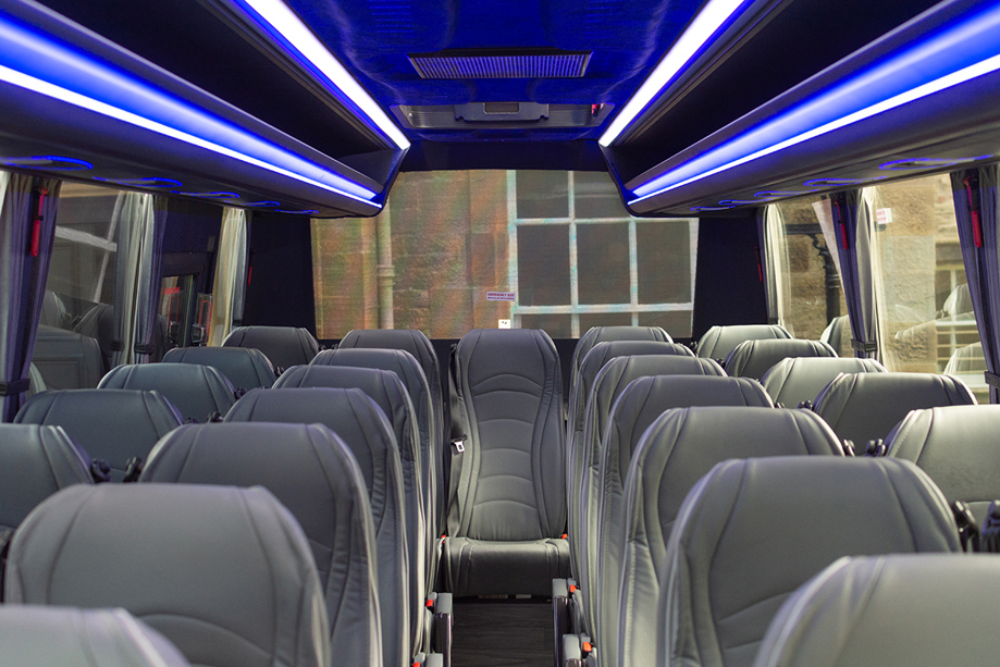 Inside one of Anderson Black Executive Travel's modern buses, with grey leather seats and blue overhead lighting