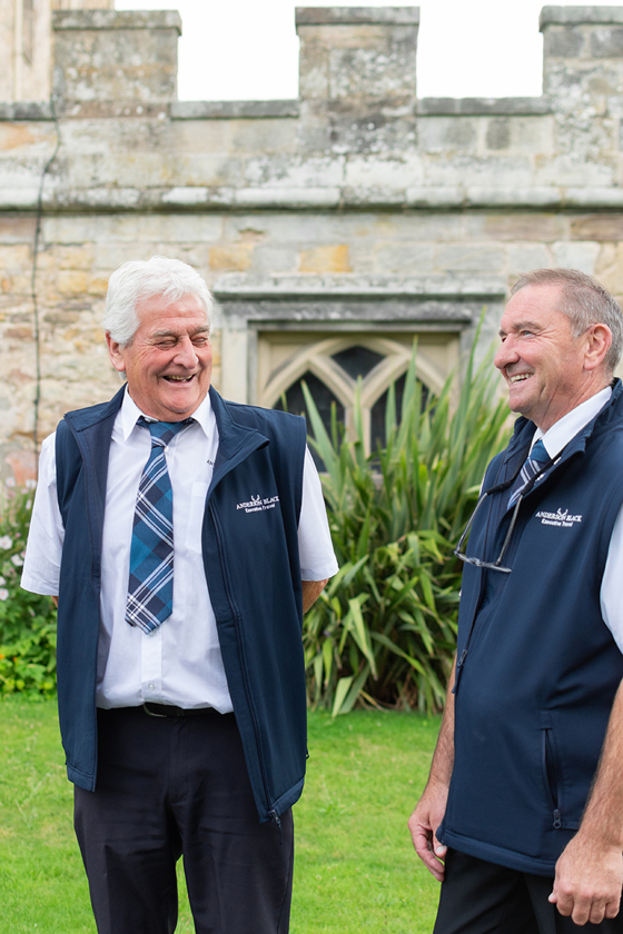 Two Anderson Black Executive Travel bus driver's laughing in professional uniform outside wedding venue